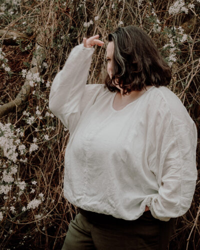 Biała lniana bluzka damska plus size z długim rękawem w plenerowej stylizacji.