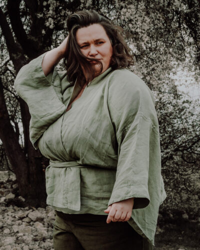Zielone kimono lniane plus size na modelce, ujęcie z boku prezentujące luźny rękaw i dopasowanie fasonu.