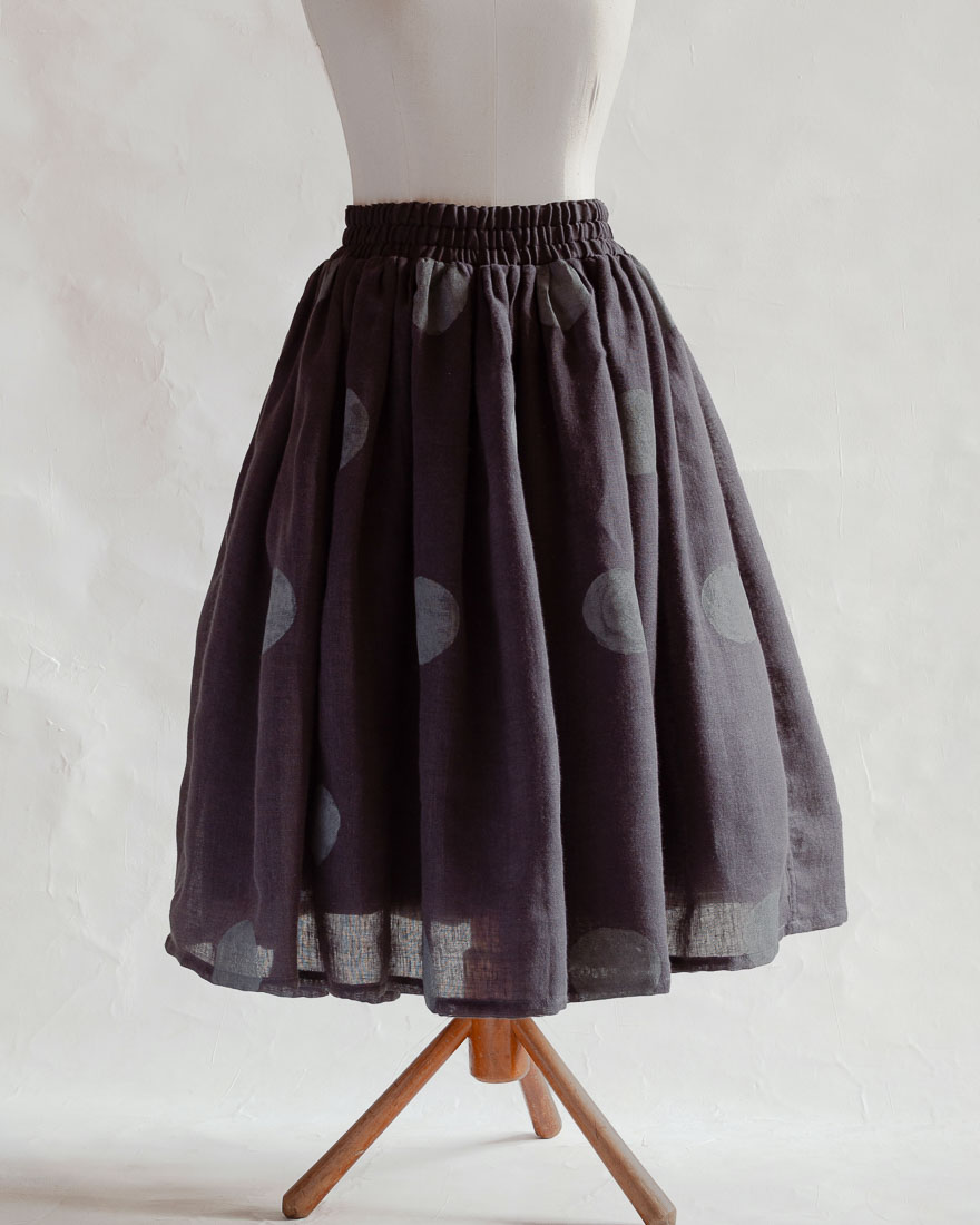 Spódnica ciemnoszara antracytowa czarna warstowa lekko rozkloszowana na podszewce bawełnianej w certyfikatem GOTS z falbaną. Drukowana w jasno szare kropy grochy . Polka dot
